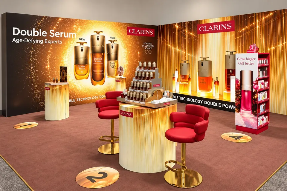 Clarins Double Serum exhibition graphics, gold printed display plinths and red consultation seating