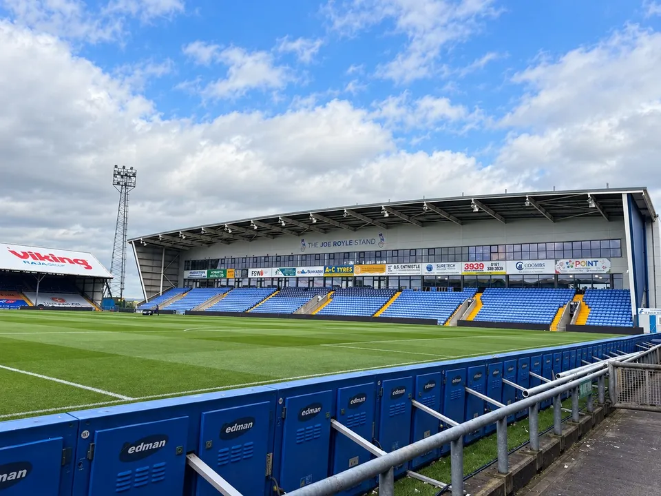 Wide view of Oldham Athletic stadium sponsor branding and the Joe Royle Stand