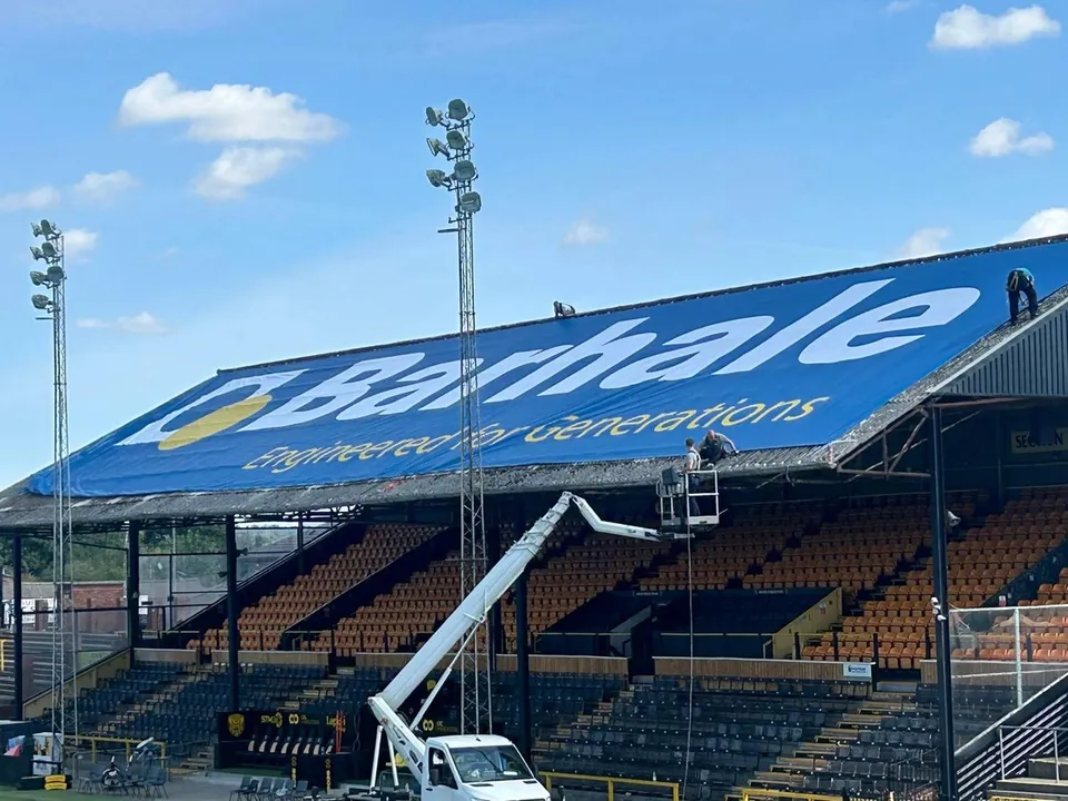 High-level installation of the Castleford Tigers stadium banner with access equipment and installation team